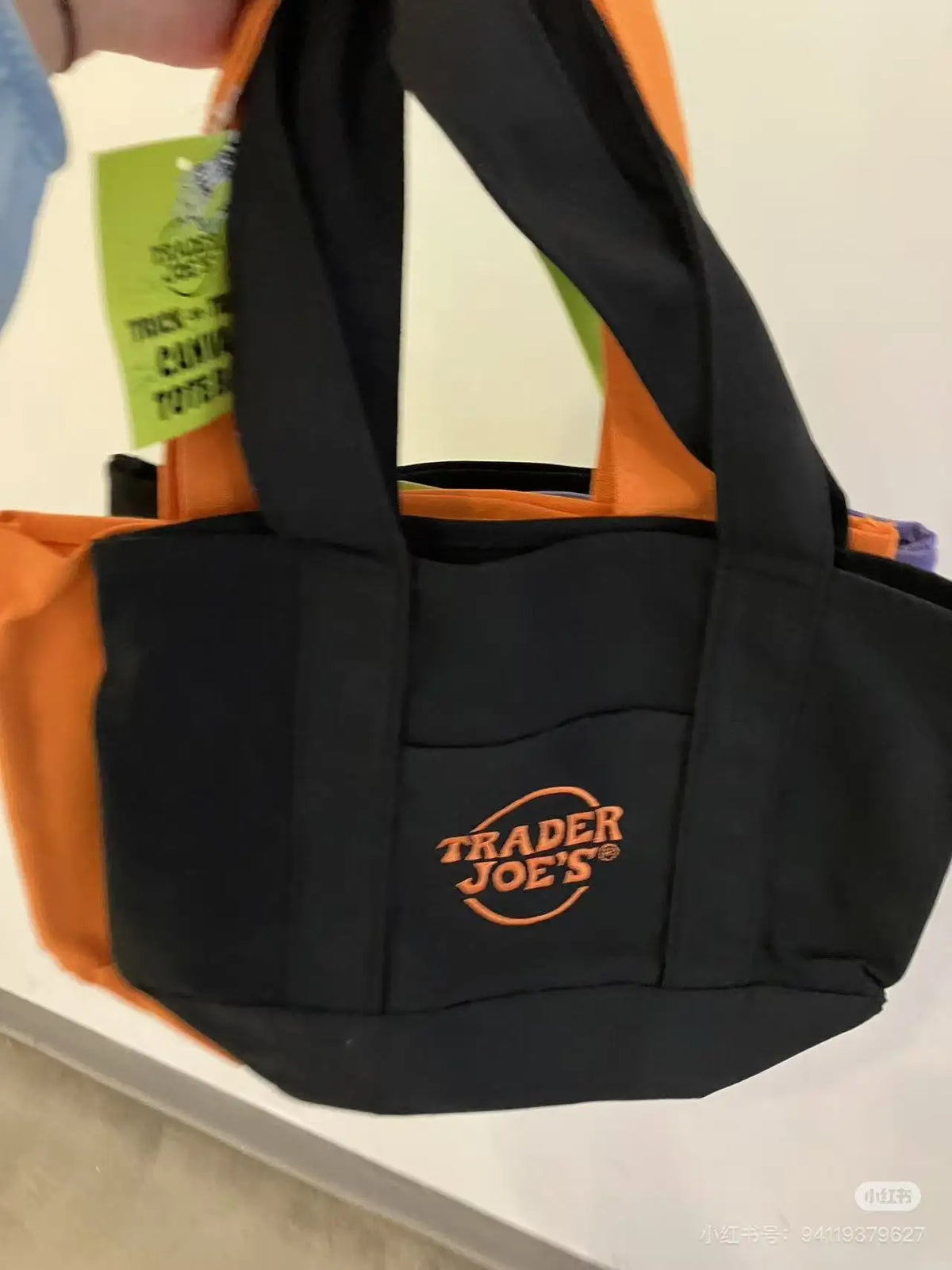 A black canvas bag with an orange strap and a Trader Joe's logo on the front.