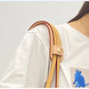A close-up of a tan leather carry loop attached to a white shirt sleeve.