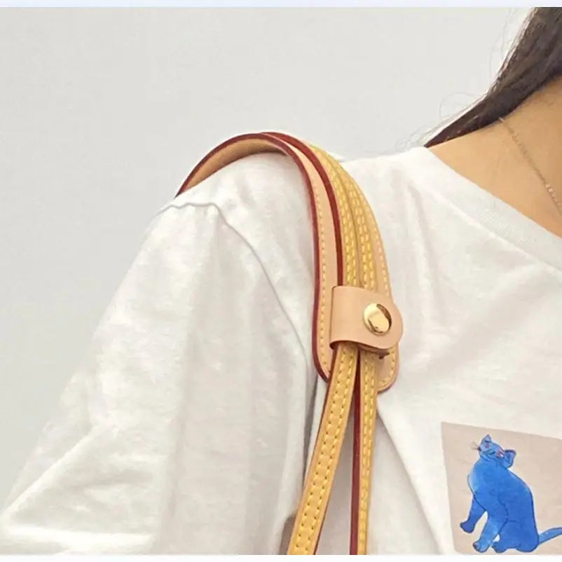 A close-up of a tan leather carry loop attached to a white shirt sleeve.