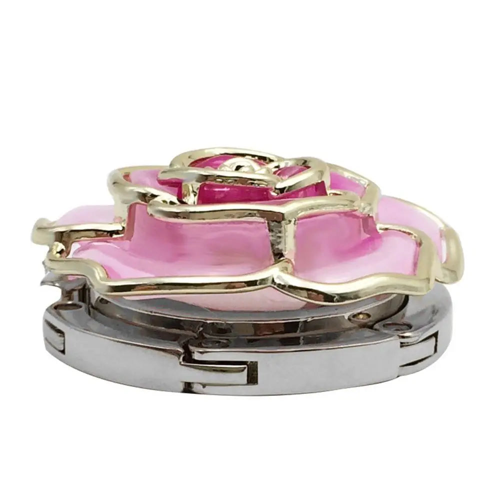 A heart-shaped metal foldable bag hook with a pink and gold floral design.