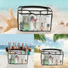 A black waterproof transparent beach bag organizer filled with various skincare and beauty products on a sandy beach.