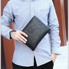 A man wearing a light gray shirt holds a black PU leather clutch wallet.