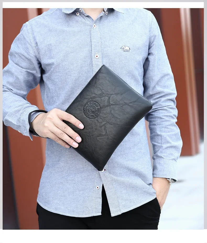 A man wearing a light gray shirt holds a black PU leather clutch wallet.