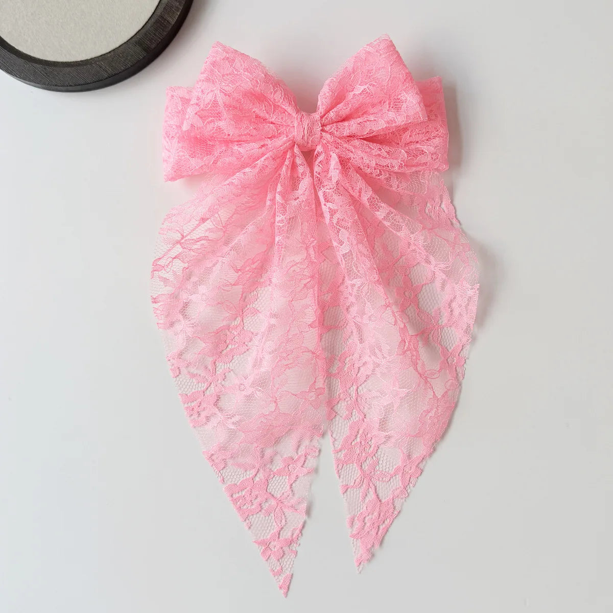 Pinkes Spitzenbindchen für eine Haarnadel, präsentiert auf weißem Untergrund.
