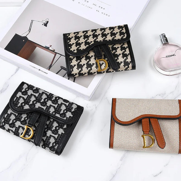 A black and white checkered faux leather card holder wallet with gold hardware displayed on a marble surface.