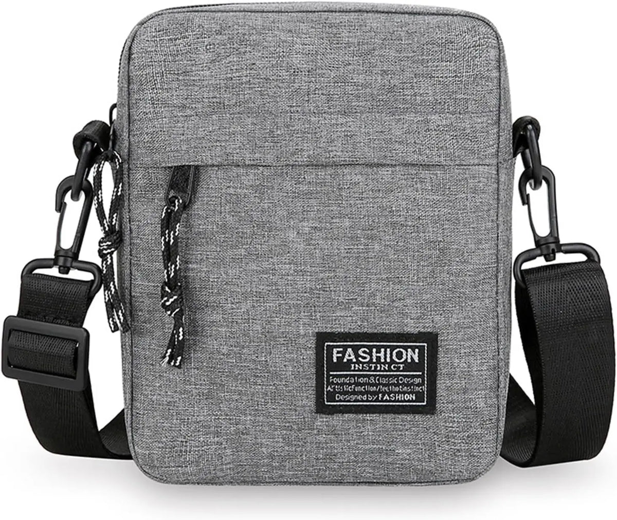 A gray nylon sling bag with black adjustable straps and a black leather tag on the front.