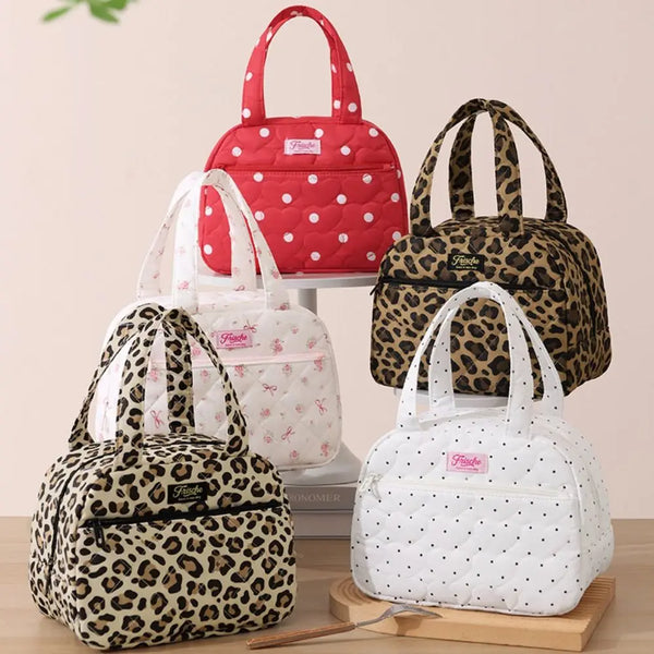 A collection of red, white, and black leopard print insulated lunch totes displayed on a wooden surface.