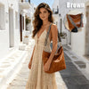 A model wearing a beige crocheted dress and carrying a brown leather crossbody bag with a patterned strap on a sunny street.