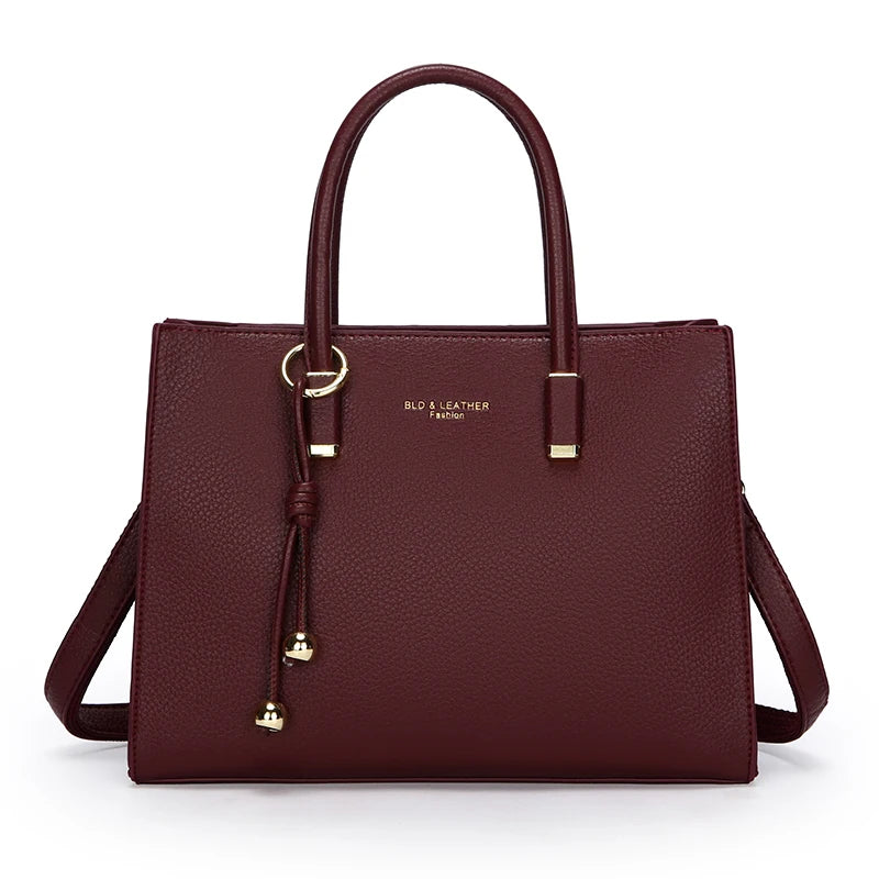 Maroones Leder-Tasche mit goldfarbenen Ziergriffen vor weißem Hintergrund.