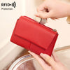 محفظة حمراء ثلاثية الطي بتقنية RFID لحماية البطاقات، تُمسك بيد وتُظهر ميزتها الواقية.
