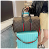 A woman holds a brown plaid travel duffle bag with green trim next to a light blue suitcase.