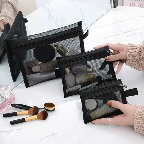 Une main tient une pochette de rangement cosmétique en filet noir remplie de pinceaux et d'outils de beauté sur une surface e