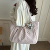 A light pink retro polka dot shoulder tote bag carried by a person in a white dress.