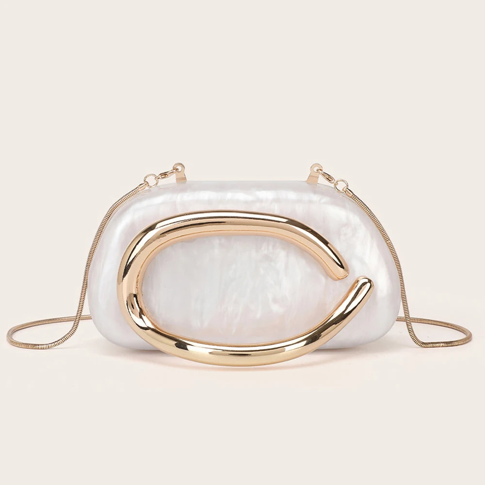 Elegant gold-tone evening clutch bag with a curved metallic gold accent on a light, iridescent white bag.