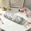 A pink quilting storage bag is displayed on a white table next to a pink hair dryer.