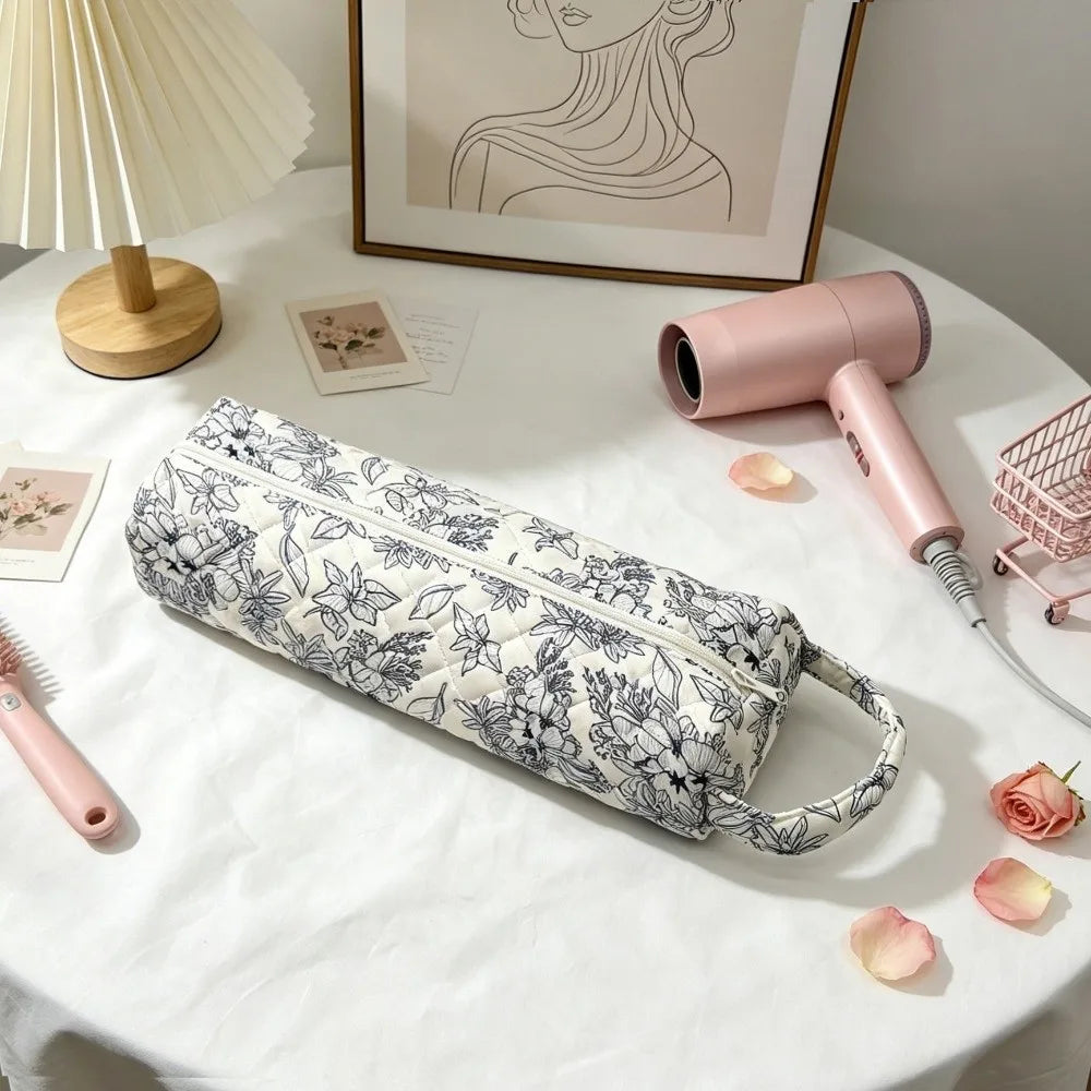 A pink quilting storage bag is displayed on a white table next to a pink hair dryer.