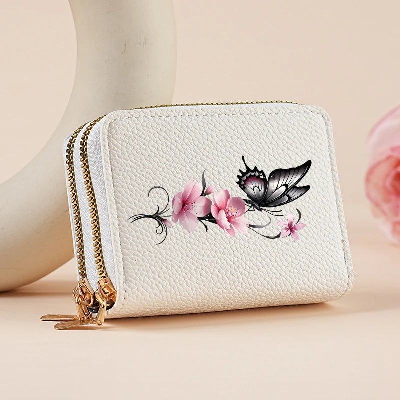 A white quilted zipper wallet featuring a pink floral and butterfly print, resting on a light background.