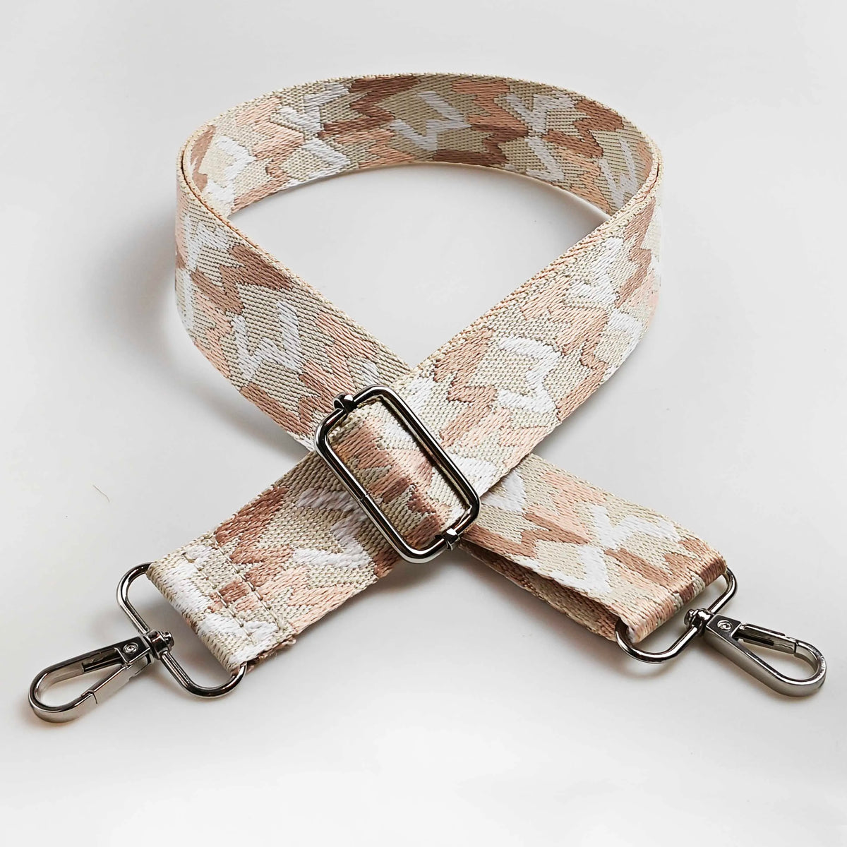 A beige and white patterned fabric strap for a crossbody bag featuring an adjustable buckle.