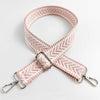 A pink woven handbag strap with an arrow jacquard pattern, shown crossed and laid flat.