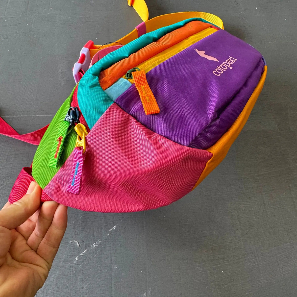 A colorful patchwork color block fanny pack featuring purple, orange, pink, and green fabric.