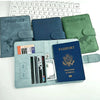 A set of elegant RFID blocking passport holders in various shades of blue, green, and gray are displayed next to a laptop key