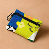 A yellow floral print mini coin purse with a black zipper and carabiner clip against a beige background.