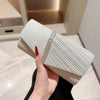Eine Hand hält eine elegante silberne Halskette als Schultertasche mit strukturiertem Silberstoff und funkelnden Verzierungen