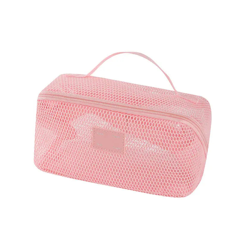 A pink mesh cosmetic organizer pouch with a handle for storing makeup and toiletries.