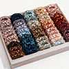 A box filled with 19 pieces of thin scrunchies hair ties in a variety of mixed satin colors.