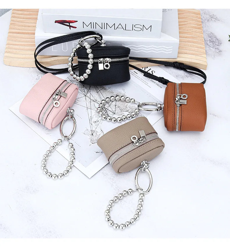 A collection of handcrafted leather coin purses and neck pendants in pink, brown, and beige with silver chains and black lany