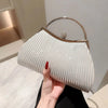 A light beige pleated glitter evening handbag with a gold top handle and chain strap being held by a hand.