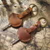A brown genuine leather key fob cover with a keychain ring and attached key.