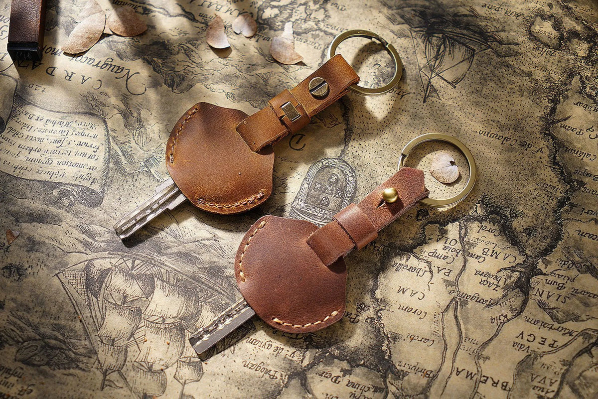 A brown genuine leather key fob cover with a keychain ring and attached key.