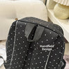 Sac à dos à pois noirs en gros plan sur fond rayé.