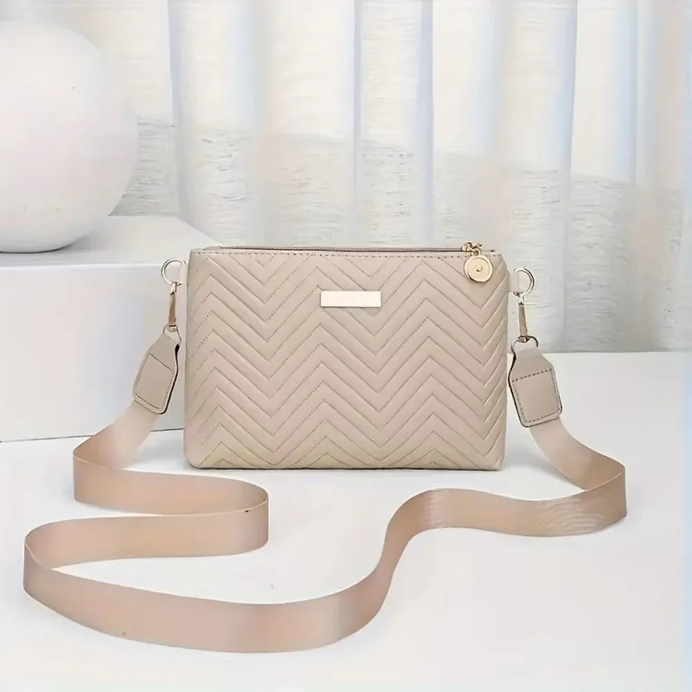 A beige quilted leather crossbody bag with a gold chain strap resting on a white surface.