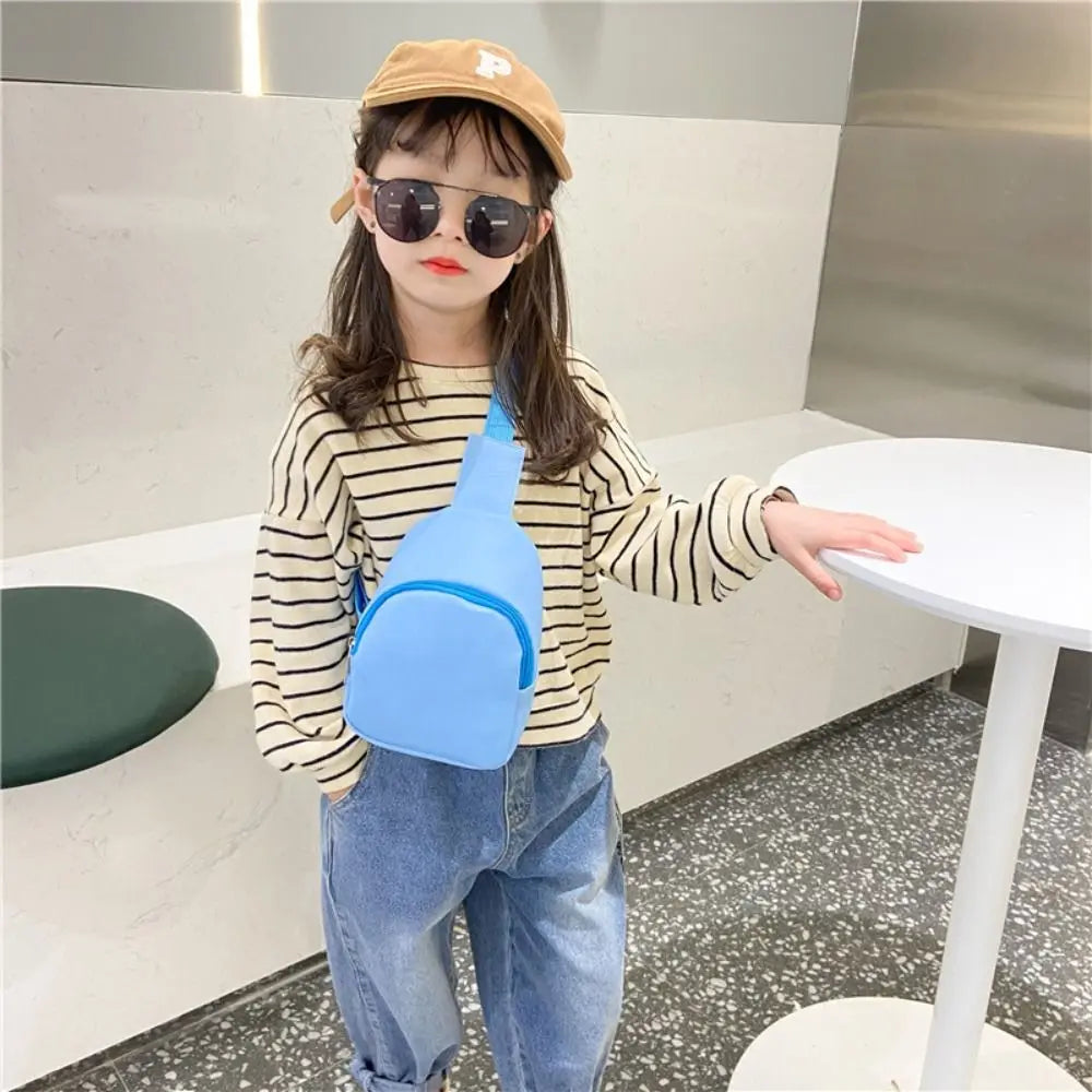 A young girl wearing sunglasses and a beige hat holds a bright blue nylon crossbody bag.