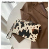 A brown blazer is shown with a white leopard print PU leather wrist bag resting on a light surface.