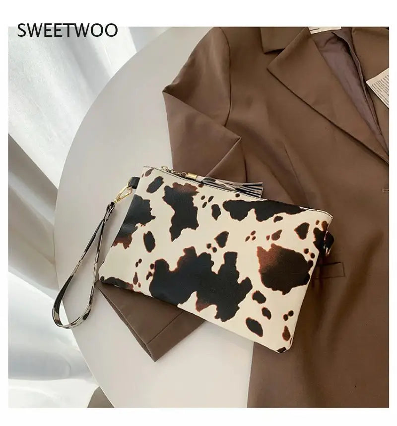 A brown blazer is shown with a white leopard print PU leather wrist bag resting on a light surface.