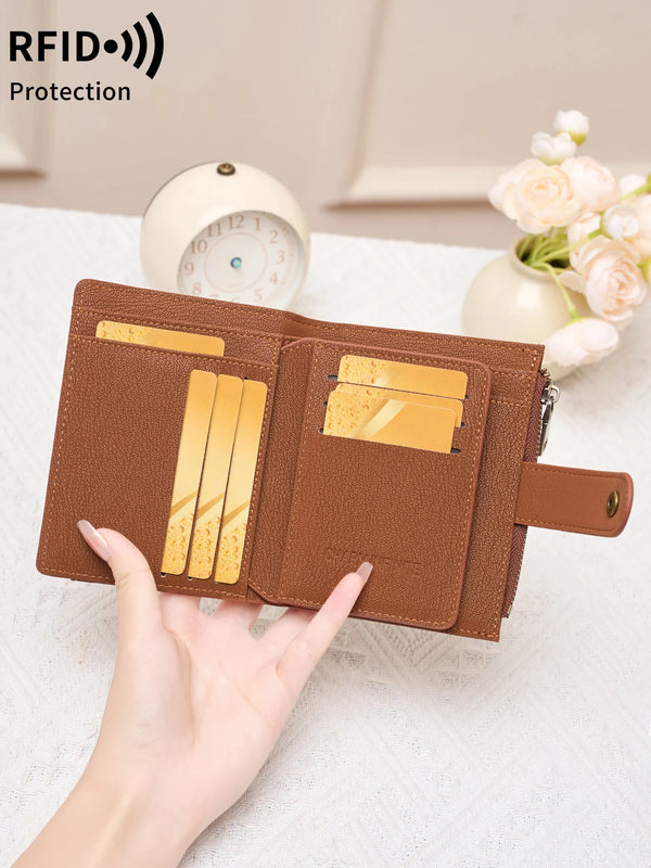 A hand holds a brown RFID-blocking compact bifold zipper wallet with gold cards and a white alarm clock in the background.
