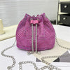 Bolso cruz con cordón de strass magenta y cadena plateada sobre superficie blanca.