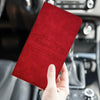 A red PU leather document organizer with a car silhouette embossed on it is held in a hand inside a car interior.