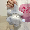 A soft gray plush elephant case for AirPods is being held by a person, displayed against a pink background.