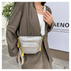 A woman wearing a brown blazer holds a light gray quilted Rivet waist bag with gold hardware.