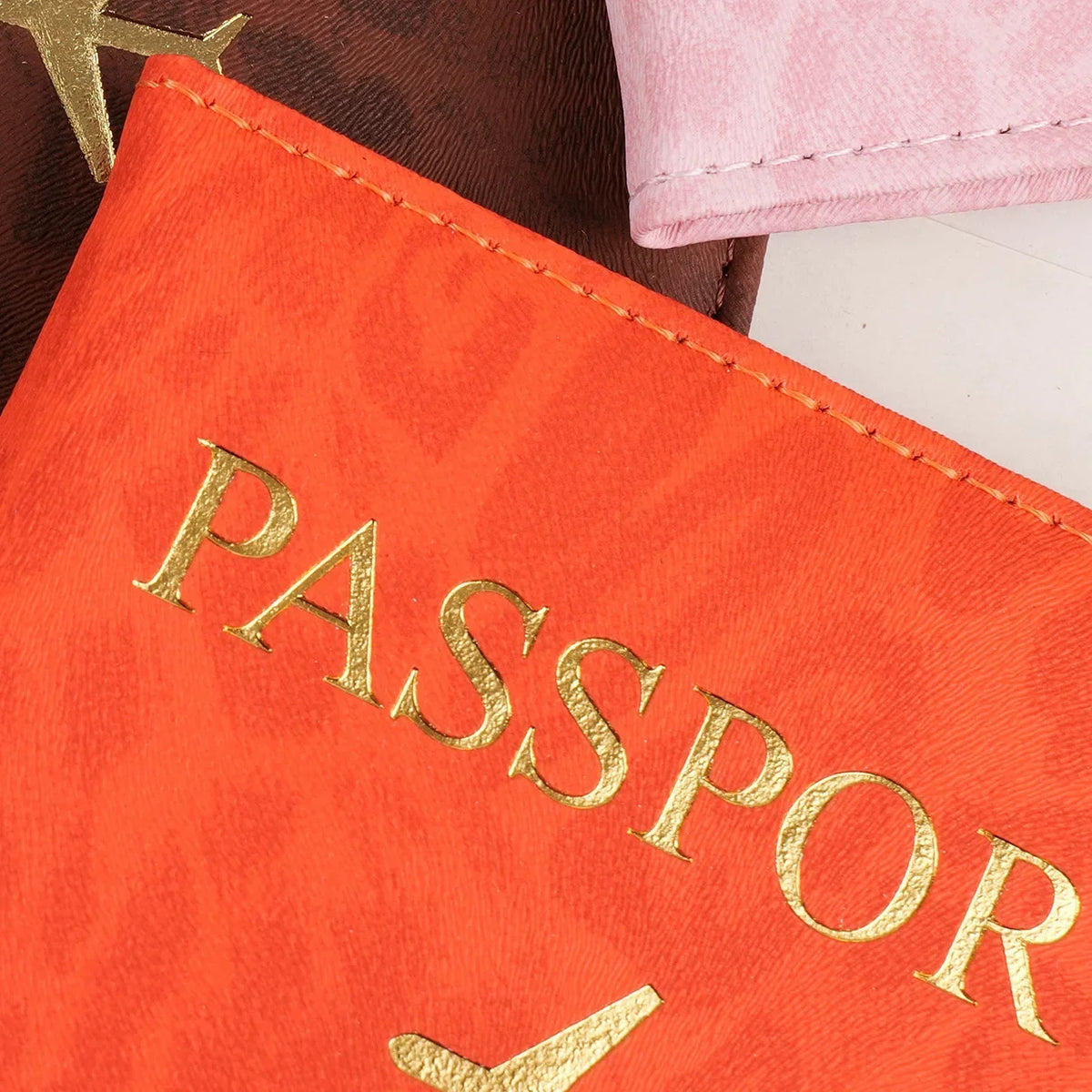 Orange passport holder with gold lettering and a leather strap visible.