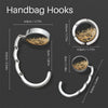 Silver handbag hooks with round metal hangers shown against a dark background.