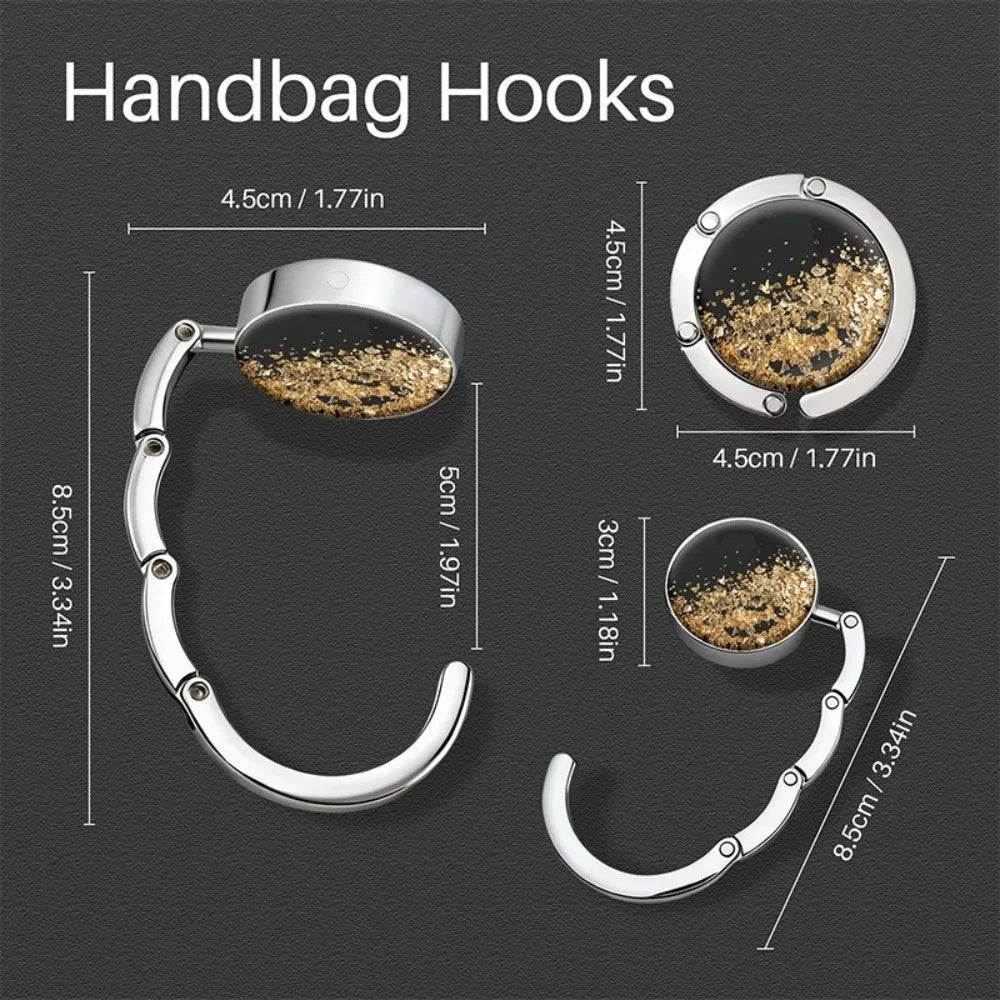 Silver handbag hooks with round metal hangers shown against a dark background.