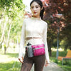 A woman wearing a white long-sleeved top and brown pants holds a pink waterproof invisible waist pack outdoors.