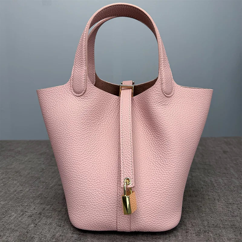 A light pink classic genuine leather bucket bag with a top handle and gold hardware.