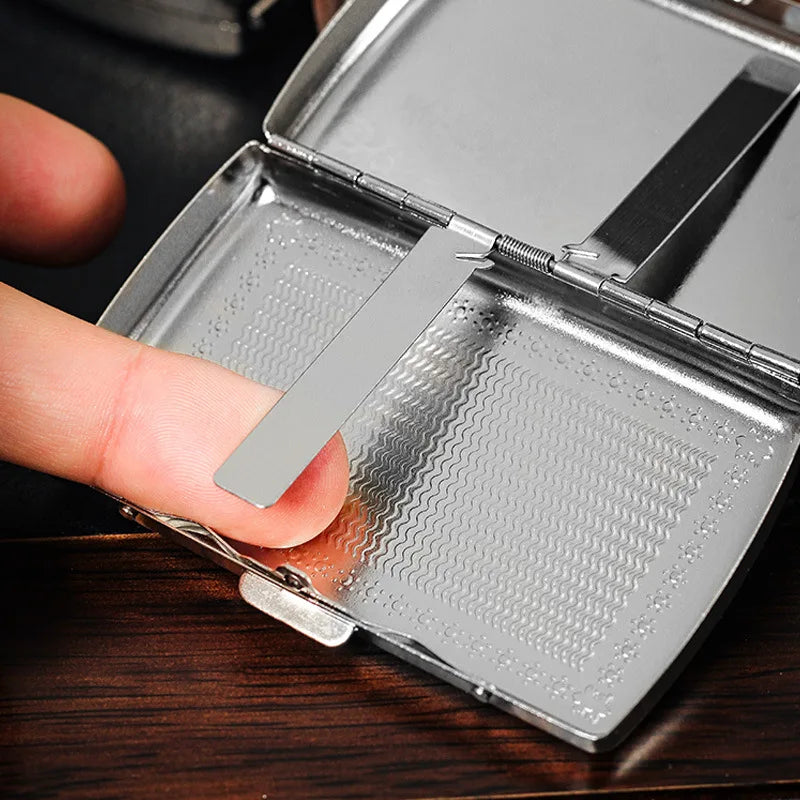 A hand opens a compact metal cigarette case, revealing a compartment for cigarettes.