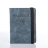 A dark blue leather passport organizer with a black strap and a silver airplane emblem.